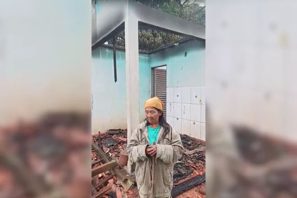 A rezadora tradicional Roberta, de 83 anos, na frente da casa destruída