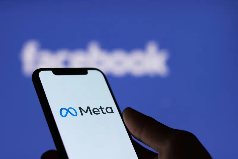 Celular com o logo da Meta e no fundo logo do Facebook